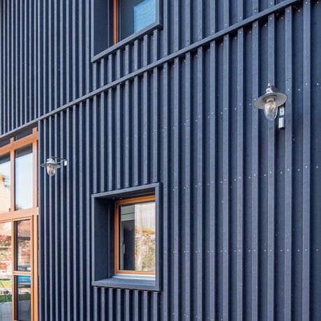Gebr. Eisenring AG, 5-0216, Fassade, nord. Fichte, Schirmbretter 20/140 und Deckleisten 50/50, sägeroh, mineralische Farbe Farbton 9008 (schwarz)